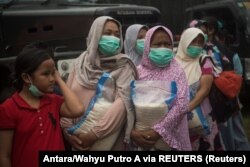 Para ibu membawa bantuan sembako di posko pengungsi di Cianjur, Jawa Barat, 24 November 2022. (Foto: Antara/Wahyu Putro A via REUTERS)