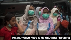 Para ibu membawa bantuan sembako di posko pengungsi di Cianjur, Jawa Barat, 24 November 2022. (Foto: Antara/Wahyu Putro A via REUTERS)