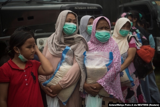 Para ibu membawa bantuan sembako di posko pengungsi di Cianjur, Jawa Barat, 24 November 2022. (Foto: Antara/Wahyu Putro A via REUTERS)