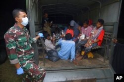 Ethnic Rohingya refugees sit at the back of a military truck after their boat landed in Pidie, Aceh province, Indonesia, Dec. 26, 2022.