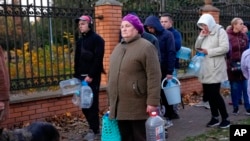 FILE - People stand in line to fill containers with water from public water pumps in Kyiv, Ukraine, Oct. 31, 2022.