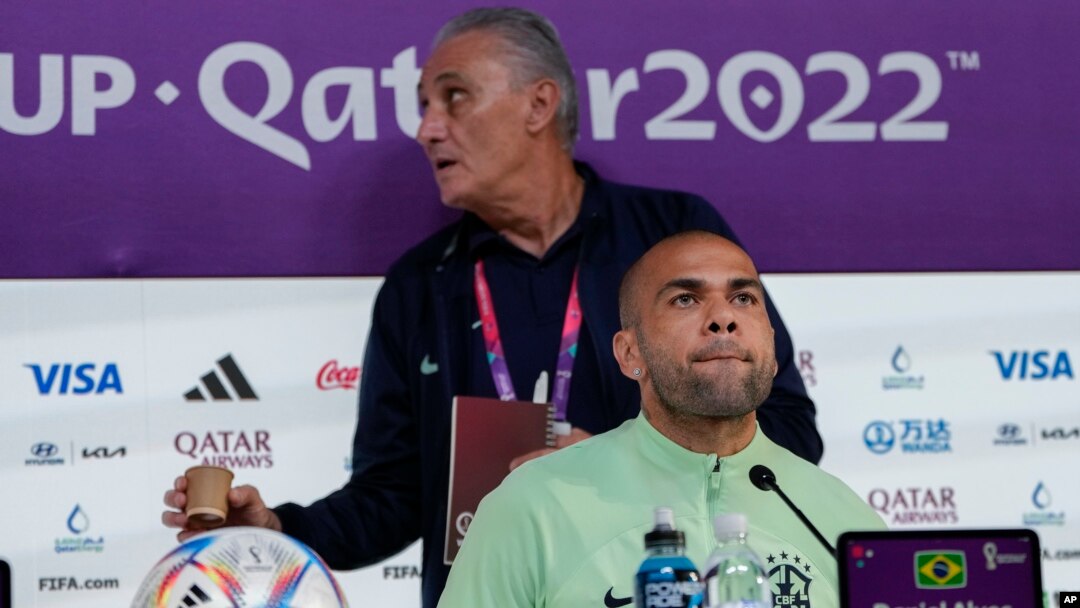 Jwe Brezilyen Dani Alves (devan) ak antrene seleksyon Brezilyen an Tite pandan yon konferans pou lapres nan Doha, Qatar, 1 Dec. 2022. 