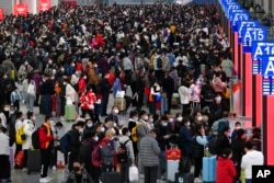 In this photo released by Xinhua News Agency, people with their luggage prepare to catch their trains at the North Railway Station in Shenzhen in south China's Guangdong province, Jan. 7, 2023.