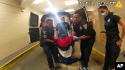 FILE - In this image taken from police body camera video provided by New Haven Police, Richard "Randy" Cox, center, is pulled from the back of a police van and placed in a wheelchair after being detained by New Haven Police on June 19, 2022, in New Haven, Connecticut. 