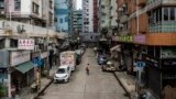 FILE - A woman walks down an empty street in the Kowloon district of Hong Kong, Nov. 22, 2022.