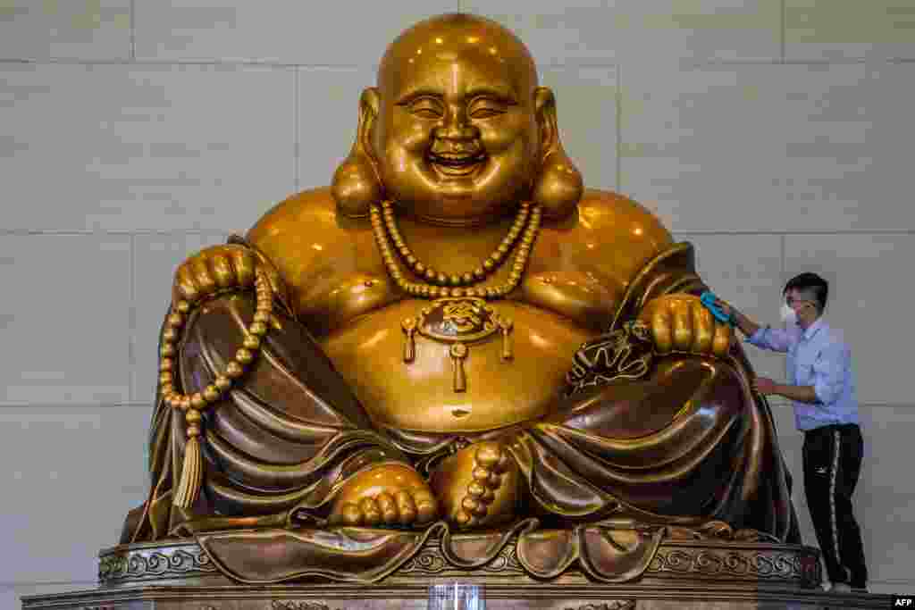 A Buddhist devotee cleans a giant Buddha statue ahead of the Lunar New Year celebrations at the Bumi Suci Maitreya Temple in Pekanbaru, Indonesia, Jan. 11, 2023.