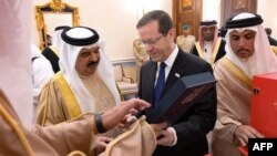 In this handout picture obtained from the Israeli Government Press Office (GPO), Bahrain's King Hamad bin Isa al-Khalifa receives a gift from Israeli President Herzog in the capital Manama, Dec. 4, 2022.