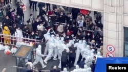 Shanghai residents confront coronavirus disease (COVID-19) staff dressed in protective clothing in Shanghai, China, in this still image obtained from a social media video released Nov. 30, 2022. Video obtained by Reuters.