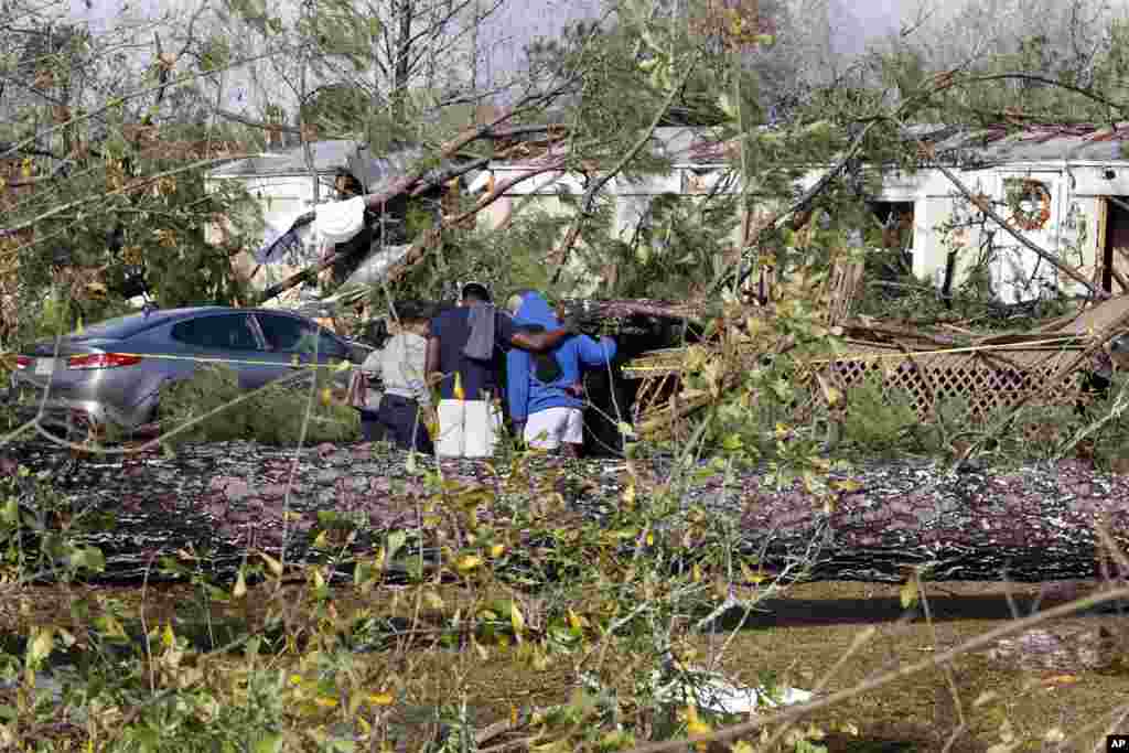 Teman dan keluarga berdoa di luar rumah mobil yang rusak di Flatwood, Alabama, sehari setelah badai hebat melanda daerah tersebut.