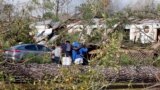 Sejumlah warga tampak berdoa di dekat sebuah rumah bergerak yang hancur diterjang tornado di Flatwood, Alabama, pada 30 November 2022. (Foto: AP/Butch Dill)