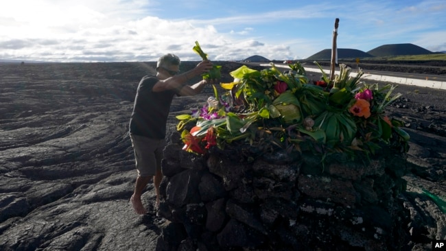 Allen Mozo leaves an offering at an alter below the Mauna Loa volcano as it erupts, Dec. 1, 2022, near Hilo, Hawaii.