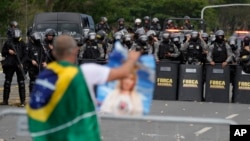 A supporter of Brazil's former President Jair Bolsonaro is confronted by a police phalanx after demonstrators stormed the Planalto Palace in Brasilia, Brazil, Jan. 8, 2023. Planalto is the official workplace of the president of Brazil.
