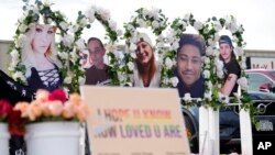 Photographs of the victims of a mass shooting a gay nightclub look over a table set with free flowers at a makeshift memorial for the victims of a mass shooting over the weekend at a gay nightclub Nov. 23, 2022, in Colorado Springs, Colo.
