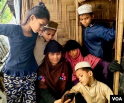 La réfugiée rohingya Surah Khatoon est assise avec ses enfants à Cox's Bazar, au Bangladesh, pour parler à sa fille Sanowara Begum - qui est en Malaisie - lors d'un appel vidéo.  Utilisant un service de bateau illégal, Sanowara a atteint la Malaisie en 2021, s'est mariée avec un Rohingya et y vit depuis.  (Mohammed Rezuwan Khan/VOA)