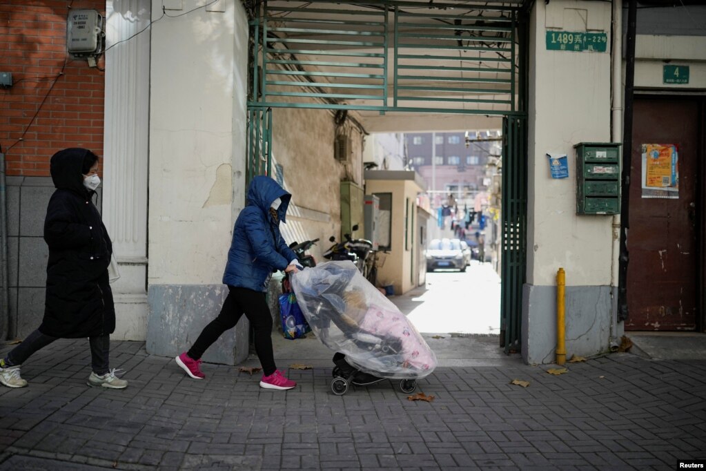 一名戴着口罩的女子推着婴儿车走过上海街头。（2022年12月18日）(photo:VOA)