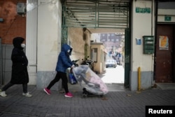 一名戴着口罩的女子推着婴儿车走过上海街头。（2022年12月18日）