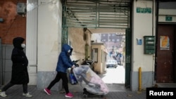 A woman wearing a face mask pushes a plastic covered stroller with a baby inside, as coronavirus disease (COVID-19) outbreaks continue in Shanghai, China, Dec. 18, 2022. 