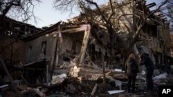 Serhii Kaharlytskyi, right, stands outside his home, destroyed after a Russian attack in Kyiv, Jan. 2, 2023. Kaharlytskyi's wife Iryna died in the attack on Dec. 31, 2022.