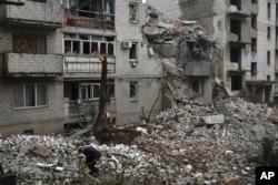 在烏克蘭恰索夫亞爾，一位男士在清理最近被俄羅斯空襲摧毀的房屋廢墟。(2022年11月27日)