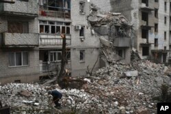 A man cleans debris of the destroyed house after recent Russian airstrike in Chasiv Yar, Ukraine, Nov. 27, 2022.