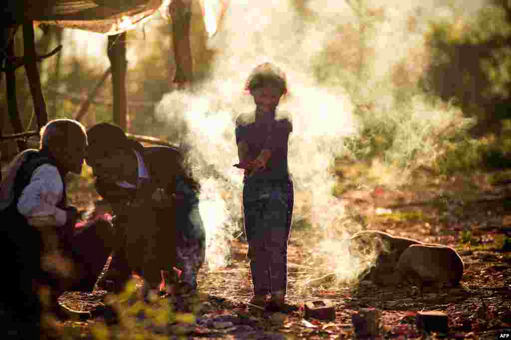 A child reacts to smoke from a bonfire lit by village elders to keep themselves warm on a wintry morning on the outskirts of Jabalpur, India.