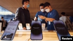 FILE - A customer talks to sales assistants in an Apple store as Apple new iPhone 14 models go on sale in Beijing, September 16, 2022. (REUTERS/Thomas Peter)