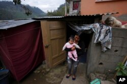 Single mother Katherine Gualotuna holds her four-month-old daughter Arleth outside a one-bedroom shack where they live with Gualotuna's parents in Zámbiza, a rural town northeast of Quito, Ecuador, Nov. 15, 2022.