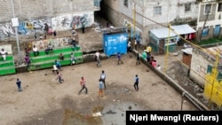 Anak laki-laki bermain sepak bola di lapangan yang basah kuyup dekat daerah kumuh lembah Mathare di Nairobi, Kenya, 1 Mei 2018. (Foto: REUTERS/Njeri Mwangi)