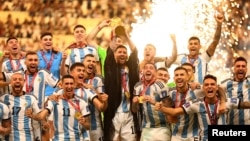 Bintang Argentina Lionel Messi (tengah) mengangkat trofi Piala Dunia bersama rekan setimnya setelah mengalahkan Prancis dalam final Piala Dunia di Stadion Lusail, Qatar, Minggu (18/12). 