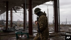 A Ukrainian serviceman patrols near the Antonovsky bridge, which was destroyed by Russian forces after withdrawing from Kherson, Ukraine, Dec. 8, 2022. 