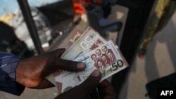 FILE—A man holds a 50 cedis, the Ghana currency, note in Accra, Ghana, on December 1, 2022. 