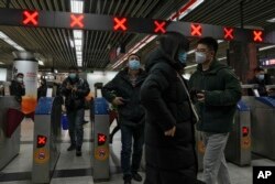 Commuters walk through a subway station during the morning rush hour in the central business district in Beijing, Tuesday, Dec. 20, 2022. China continues to adapt to an easing of strict virus containment regulations. (AP Photo/Andy Wong)