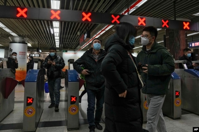 Commuters walk through a subway station during the morning rush hour in the central business district in Beijing, Tuesday, Dec. 20, 2022. China continues to adapt to an easing of strict virus containment regulations. (AP Photo/Andy Wong)