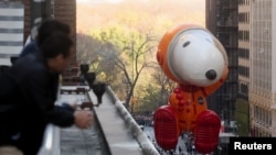 A spectator gets a closer view as Astronaut Snoopy flies by during the 96th Macy's Thanksgiving Day Parade in New York, Nov. 24, 2022.