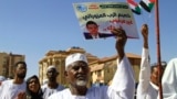 FILE: A Sudanese protester carries a placard with a crossed out portrait of the United Nations special representative in Sudan, Volker Perthes, during a march outside the UN headquarters in the Manshiya district of Khartoum, on December 3, 2022. 