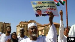 FILE: A Sudanese protester carries a placard with a crossed out portrait of the United Nations special representative in Sudan, Volker Perthes, during a march outside the UN headquarters in the Manshiya district of Khartoum, on December 3, 2022. 