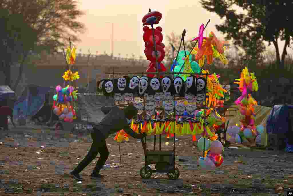 A migrant street vendor pushes his cart to work as he starts his day from his temporary shelter on a cold morning in Jammu, India.