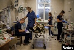 FILE - Healthcare workers treat a wounded Ukrainian soldier in a military hospital in Donetsk region, as Russia's attack on Ukraine continues, Aug. 9, 2022.