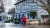 Warga tampak berjalan menerjang banjir yang merendam wiolayah Merced, California, pada 10 Januari 2023. (Foto: AP/Noah Berger)