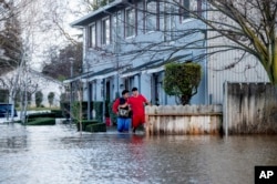Dos residentes de Merced, California, vadean una inundación el 20 de enero de 2023.