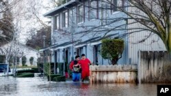 Abraham Ayala, right, wades through water in Merced, California, on Jan. 10, 2023.