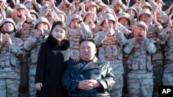 Pemimpin Korea Utara Kim Jong Un, kanan tengah, dan putrinya, kiri tengah, setelah peluncuran rudal balistik antarbenua Hwasong-17, di lokasi tak dikenal di Korea Utara. (Foto: via AP)