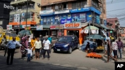 People walk past sports betting shops on a street in Lagos, Nigeria, Monday, Dec. 5, 2022. (AP Photo/Sunday Alamba)