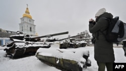 资料照片：一名女子在乌克兰首都基辅拍摄露天展示的被乌克兰摧毁的俄罗斯坦克。(2022年12月12日)