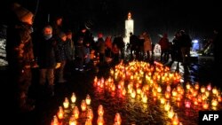 Local residents light candles during ceremony at a monument of the victims of the Holodomor, Ukrainian for "death by starvation," in Kyiv, Nov. 26, 2022, amid the Russian invasion of Ukraine.