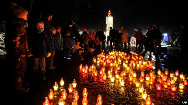 Local residents light candles during ceremony at a monument of the victims of the Holodomor, Ukrainian for "death by starvation," in Kyiv, Nov. 26, 2022, amid the Russian invasion of Ukraine.