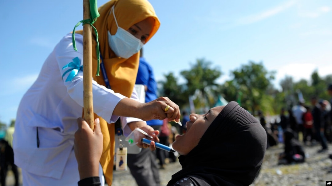 A medical worker gives drops of vaccine to a girl during a polio immunization campaign at Sigli Town Square in Pidie, Aceh province, Indonesia, Nov. 28, 2022. 
