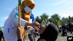 A medical worker gives drops of vaccine to a girl during a polio immunization campaign at Sigli Town Square in Pidie, Aceh province, Indonesia, Nov. 28, 2022. 