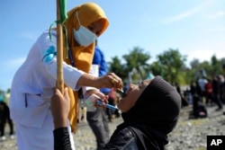 Seorang petugas medis memberikan vaksin kepada seorang anak perempuan saat kampanye imunisasi polio di Alun-Alun Kota Sigli di Pidie, Aceh, 28 November 2022. (Foto: AP)