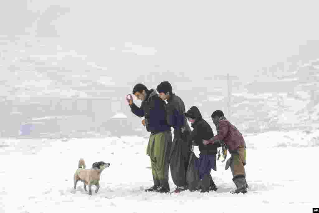 Afghan boys enjoy their time playing in a snowy day on the outskirts of Kabul, Afghanistan, Jan. 11, 2023. 